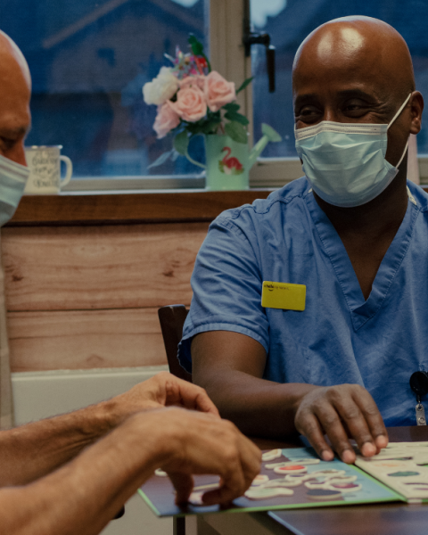 healthcare support worker sitting at a table with patient