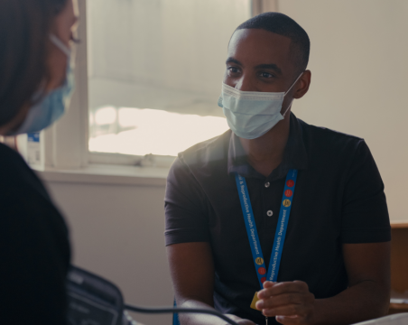 nurse with mask talking to patient