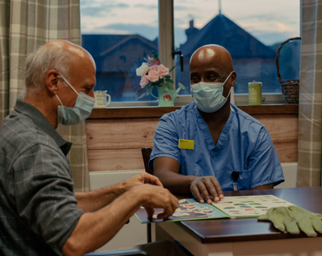 healthcare support worker sitting at table with patient