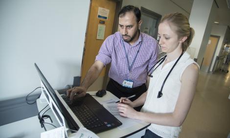 Male and female doctors looking at laptop