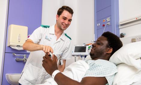 nursing associate smiling at patient in bed