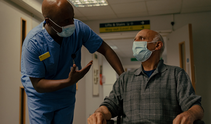 healthcare support worker standing up talking to patient in chair