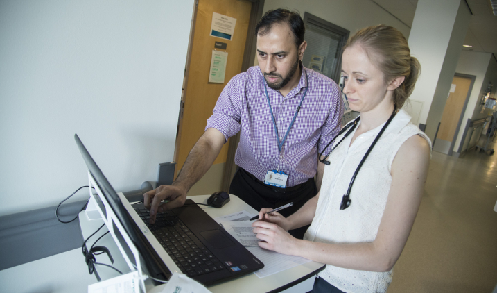 Male and female doctors looking at laptop