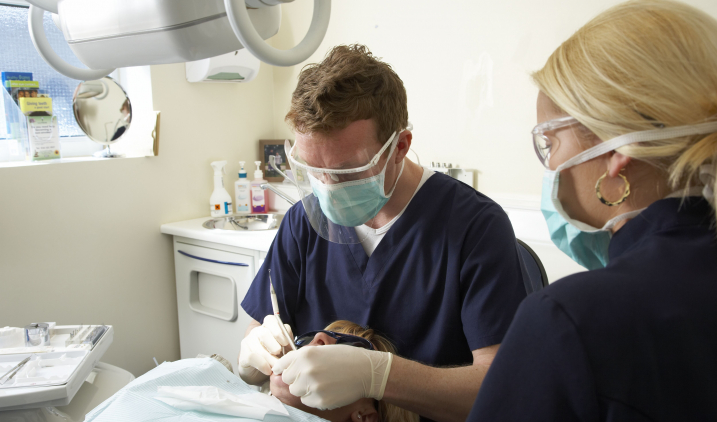 dental-male-and-female-colleague-treating-patient's-teeth